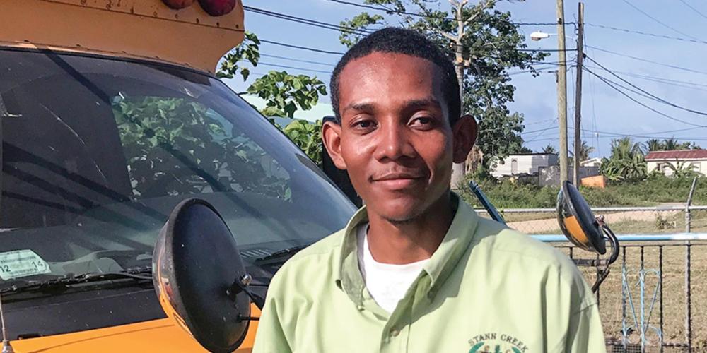 Angel Sabal, 24, standing near a school bus in Dangriga Town, Belize. (Andrew McChesney / Adventist Mission)