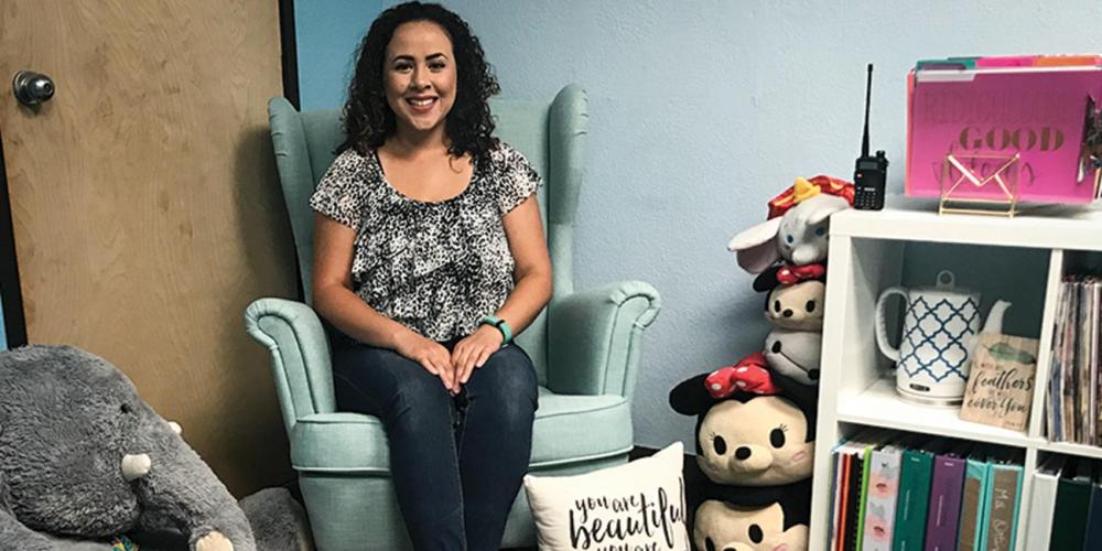 Giselle Ortiz, 27, case manager at Holbrook Indian School, posing in the chair in her office where students usually sit. (Andrew McChesney / Adventist Mission)